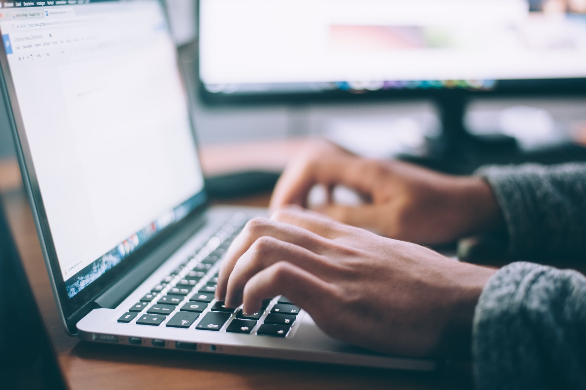 Hands shown typing on a laptop